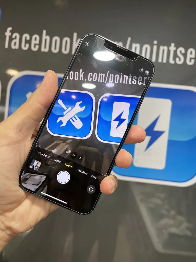 Vérification d'un iPhone en main au comptoir de Point Service Phone à Mantes-la-Jolie