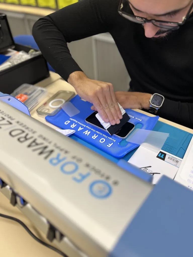 Pose d'un film de protection d'écran sur un smartphone en boutique à Mantes-la-Jolie